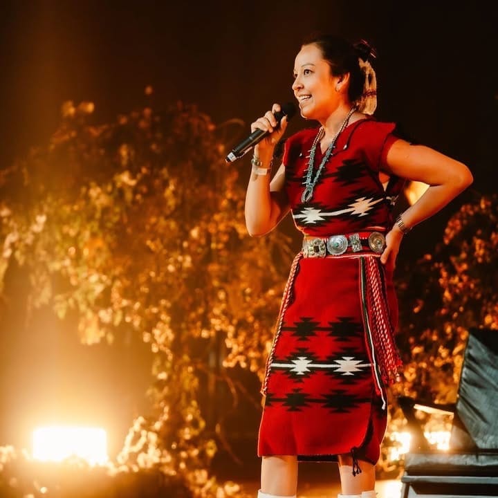 Lyla June Johnston presenting on stage at Earthed Summit, wearing traditional indigenous clothing